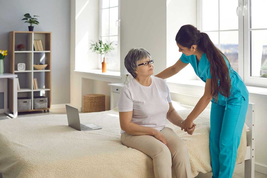 Nursing assistants helping elderly residents with daily activities in a shared living room.